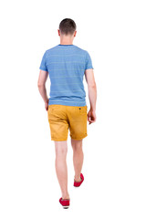Back view of going  handsome man in shorts.  walking young guy