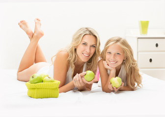 Beautiful mother and daughter together with apple