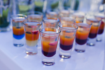 Beautiful line of different coloured cocktails on a open air par