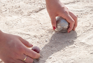  Hands picking up a petanque ball and the jack