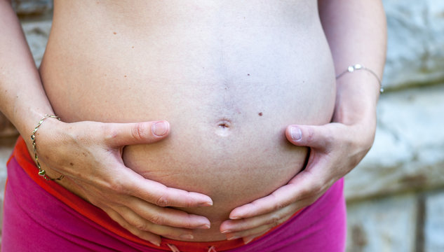 Pregnant woman embracing belly with her hands