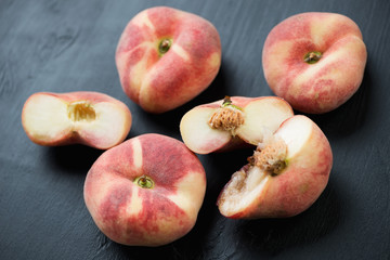 Ripe donut peaches over black wooden surface, high angle view