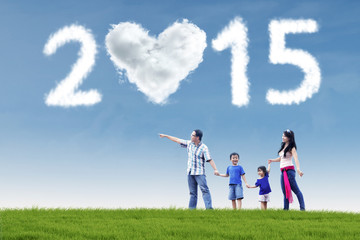 Happy family in field under cloud of 2015
