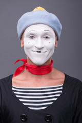 Portrait of male mime with grey hat and white face grimacing wit