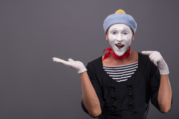 Portrait of male mime with grey hat and white face grimacing wit