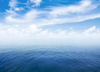 blue sea or ocean water surface with horizon and sky with clouds
