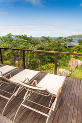 Sunbathing chairs on wooden decking with blue ocean view