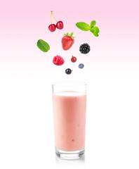 Delicious fresh berries falling into glass of yogurt