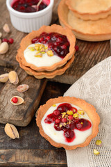 tartlets with cream, berry sauce and pistachios