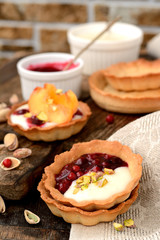 tartlets with cream, berry sauce and pistachios