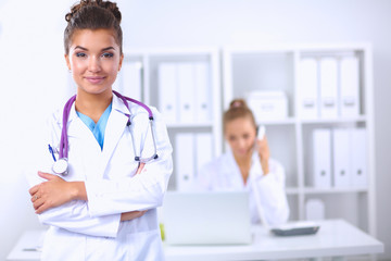 Fototapeta premium Portrait of young woman doctor with white coat standing in hosp