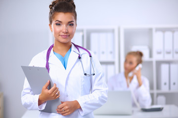 Fototapeta premium Smiling female doctor with a folder in uniform standing at hosp
