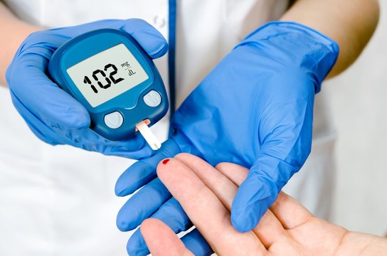 Doctor woman measuring glucose level blood in hospital close-up