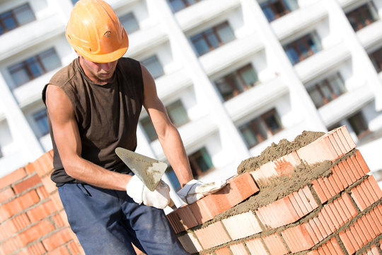 Construction bricklayer worker installing brick with trowel
