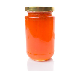 Orange fruit jam in a bottle over white background