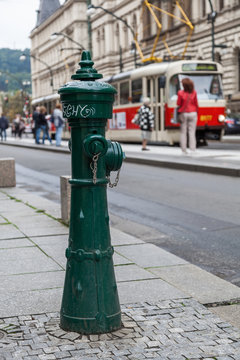antiker Hydrant mit einer Prager Straßenszene im Hintergrund