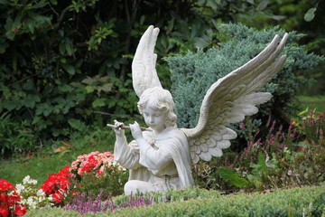 Engel musiziert zwischen Blumen auf Friedhof
