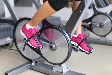 Exercise bike with spinning wheels - woman biking - obrazy, fototapety, plakaty