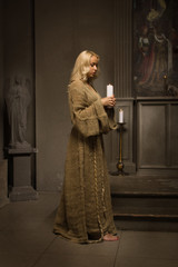 Fototapeta na wymiar Nun praying in a medieval church