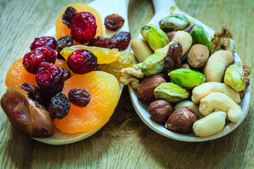 Varieties of dried fruits and nuts on wooden spoons.