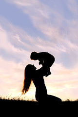 Silhouette of Happy Mother Playing Outside with Baby