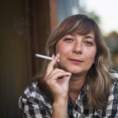 Young woman with a cigarette, outdoors. Close-up portrait.