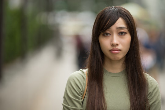 Young Asian woman in city sad face portrait