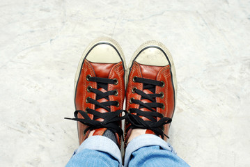 Feet in sneaker on concrete floor.