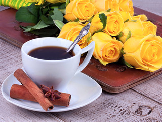 Cup of coffee and roses over wooden background