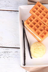 Tasty belgian waffles with ice cream on wooden table