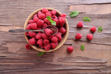 Ripe sweet raspberries in bowl on table close-up