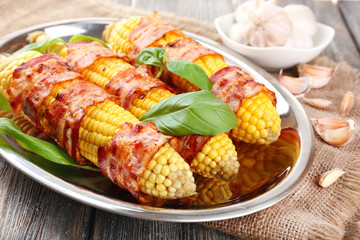 Grilled bacon wrapped corn on table, close-up
