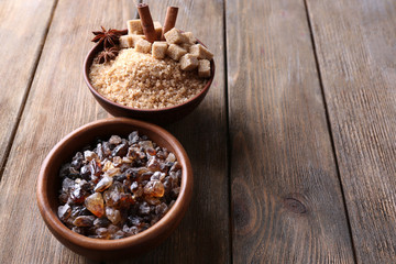 Obraz na płótnie Canvas Brown sugar cubes, reed and crystal sugar in bowls