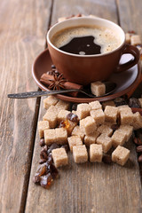 Brown sugar, spices and cup of coffee on wooden background