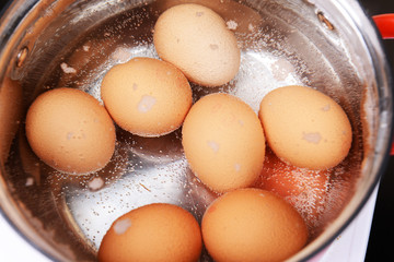 Eggs in boiling water in pan on electric hob