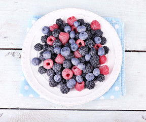 Iced berries on plate, on color wooden background