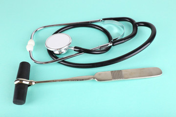 Stethoscope and reflex hummer on light background