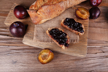 Bread with plum jam on wooden table close-up