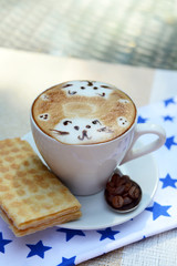Cup of coffee with cute drawing on table, close up