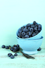 Tasty ripe blueberries in cups, on wooden table