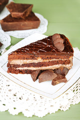 Chocolate cake on plate on color wooden background
