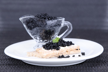 Slice of bread with butter and sauceboat with caviar