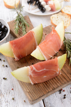 Delicious melon with prosciutto on table close-up