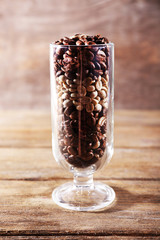 Glass of coffee beans on wooden table on wooden background