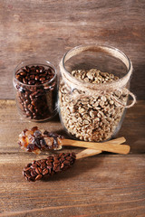 Glass jars and spoon of coffee beans on wooden background