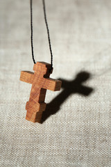 Wooden cross with deep shadow on wooden background