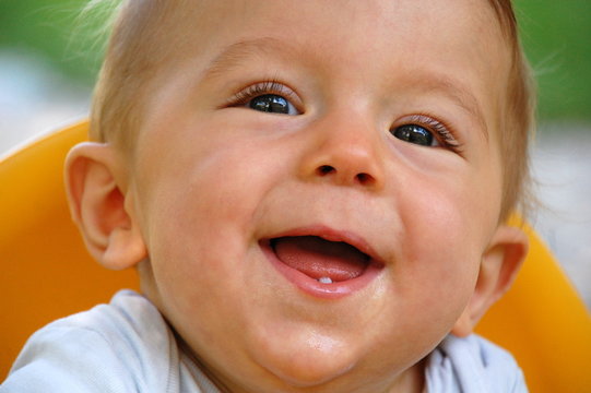 Lachendes Baby (Junge) mit erstem Zahn
