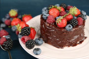 Tasty chocolate cake with different berries, on wooden table