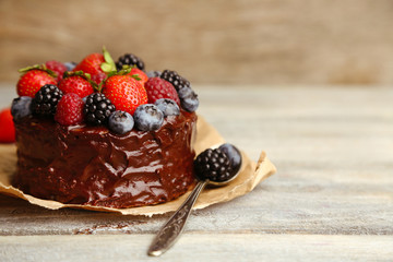 Tasty chocolate cake with different berries on wooden table