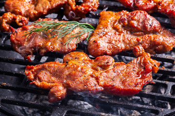 Grilling pork steaks on barbecue grill